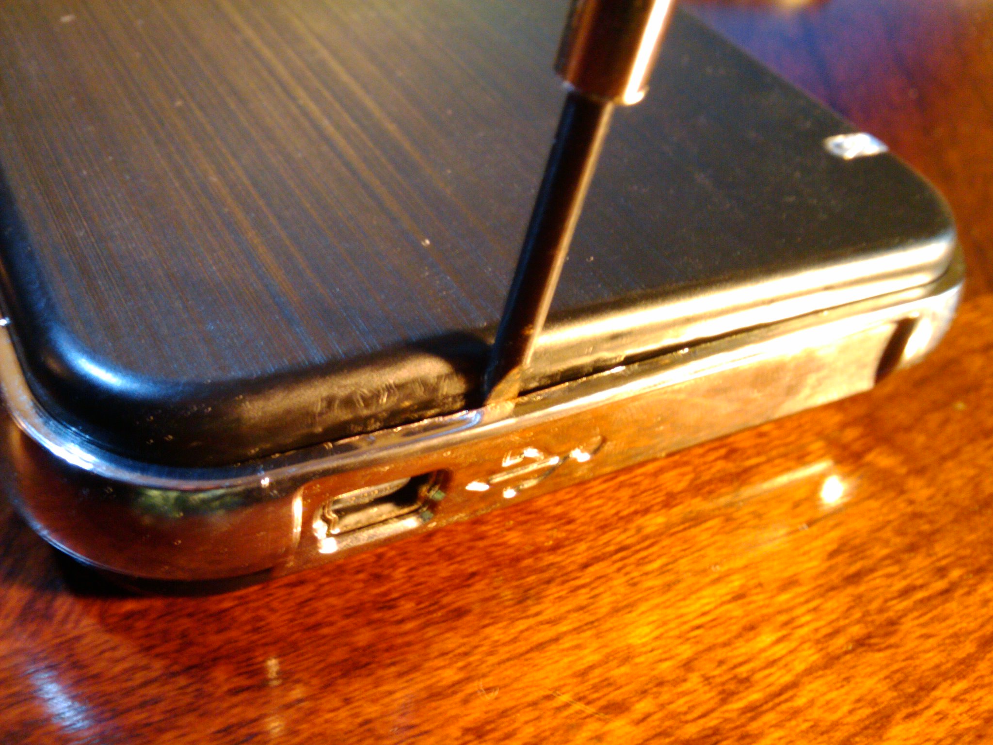 Wedge the screwdriver between the black plastic and the chrome