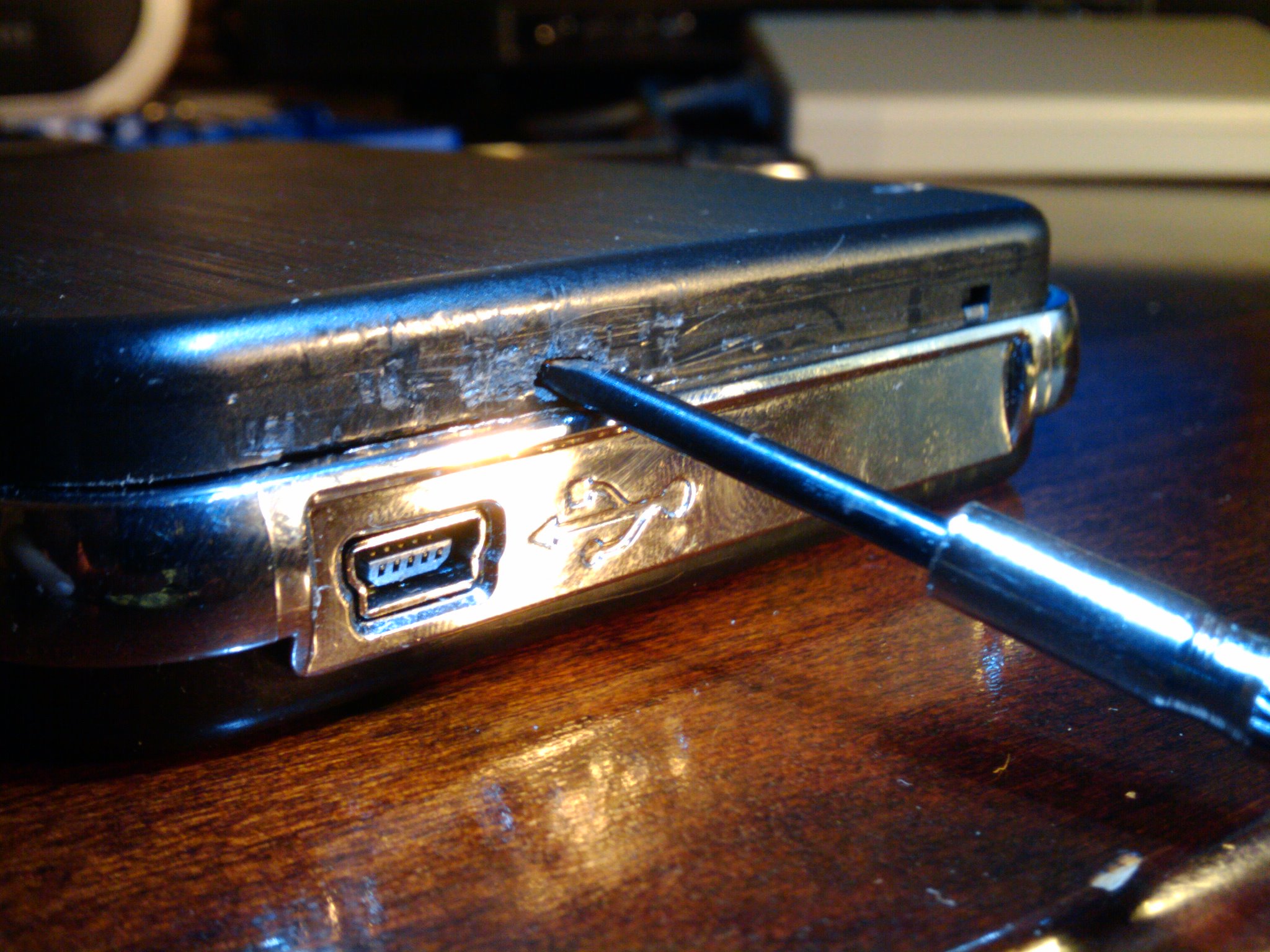 You want to hook the end of the screwdriver into a little hole that’s behind the USB logo